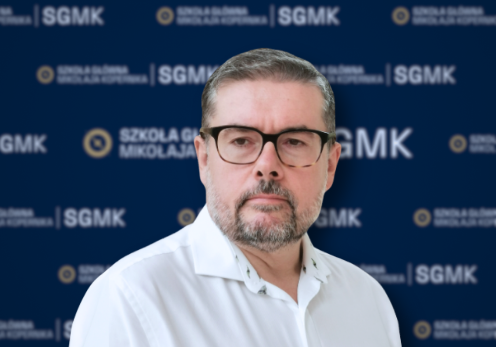Zdjęcie portretowe Mirosława Lenarta na tle ścianki z logotypami Szkoły Głównej Mikołaja Kopernika.