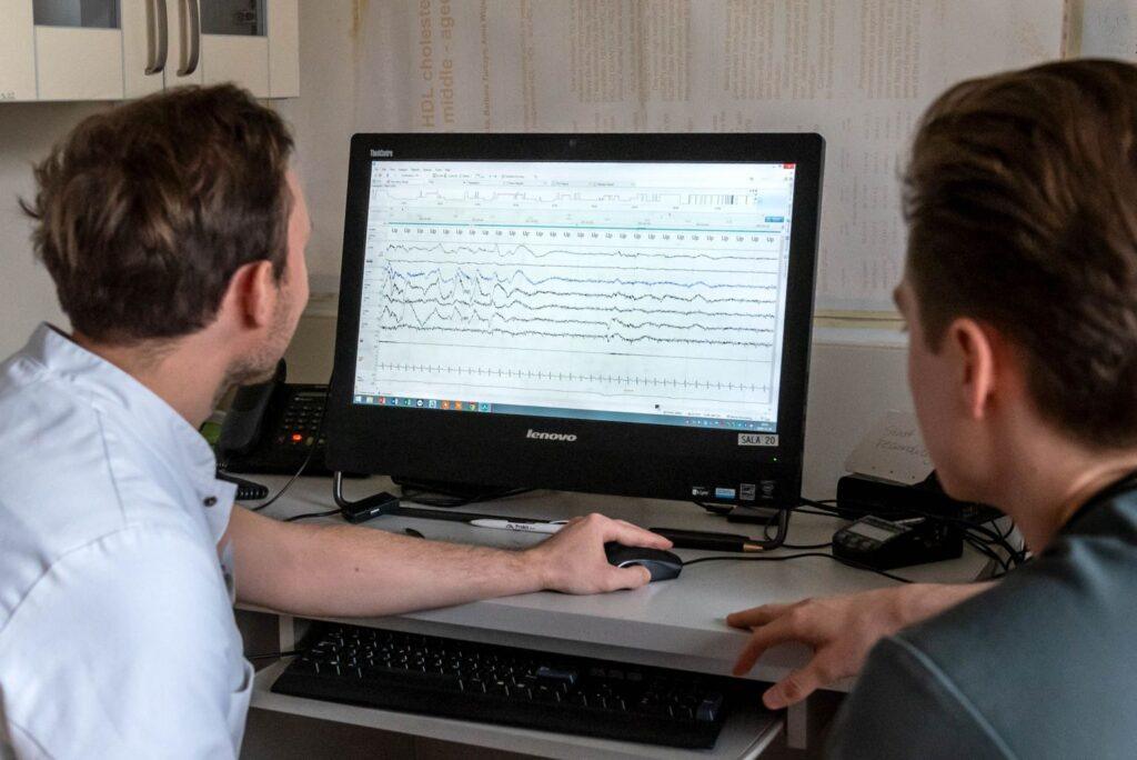 dwóch mężczyzn przy monitorze komputera analizujących wykresy