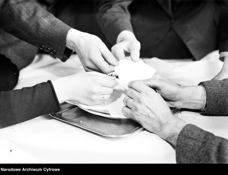 opłatek na stole, wokół sięgają po niego ręce ludzi