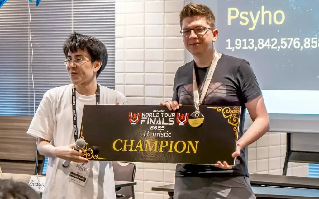 Dwaj mężczyźni trzymający tablicę z napisem AtCoder World Tour Finals 2023 Heuristic CHAMPION.