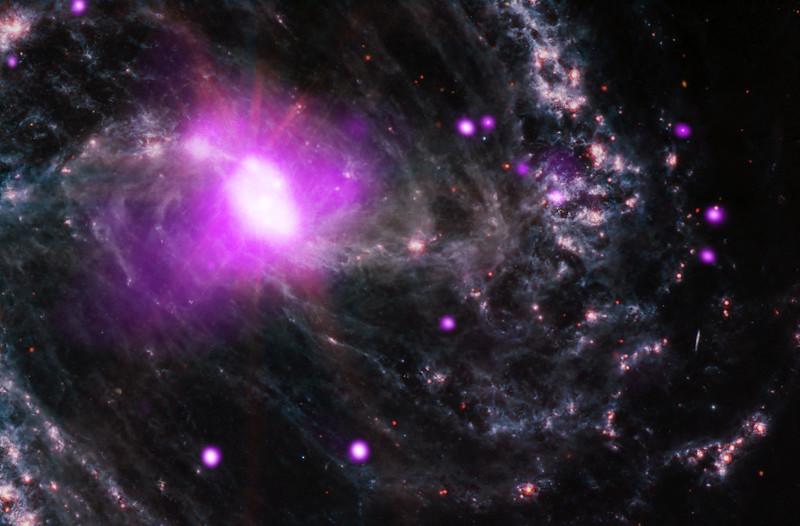 Galaktyka spiralna z fioletowymi obszarami promieniowania X i gęstym pyłem gwiezdnym na czarnym tle.