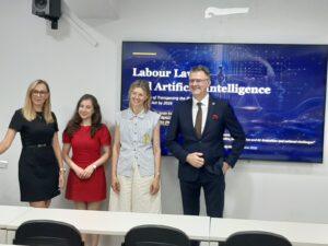 Czworo osób przed ekranem z tytułem prezentacji „Labour Law and Artificial Intelligence”.