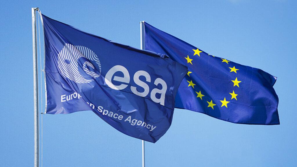 Flaga Europejskiej Agencji Kosmicznej (ESA) oraz flaga Unii Europejskiej na tle błękitnego nieba.